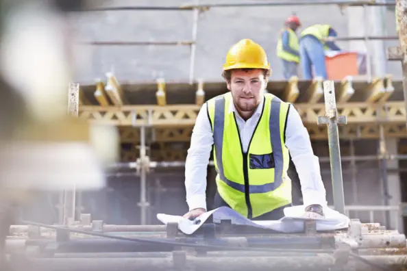 Baudarlehen: Ingenieur mit Blaupausen auf der Baustelle